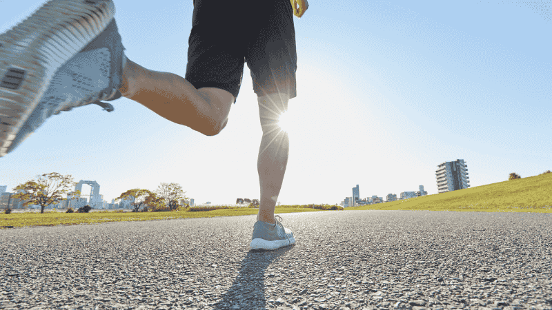 A runner wearing a lightweight performance half-zip and 5-inch shorts on a sun-dappled park path, demonstrating ideal layering for 50-degree weather.