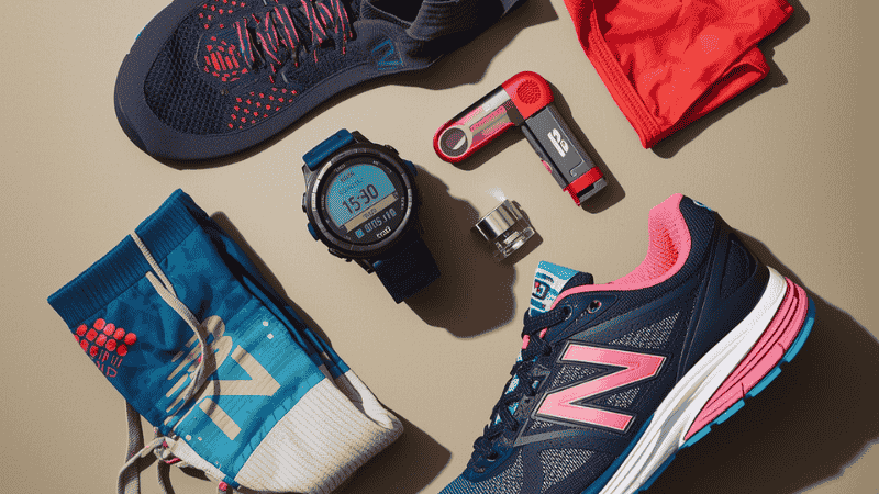 A flat display of professional running gear, including a GPS sports watch, high-performance sweat-wicking socks and a pair of New Balance 1080 v15 running shoes.