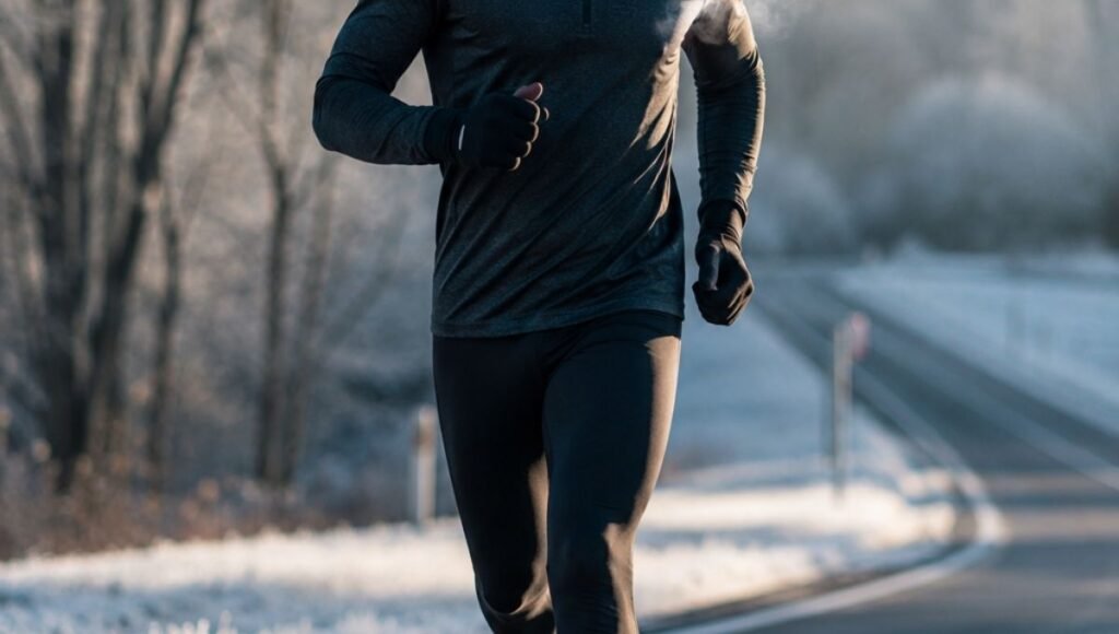 Male runner mid-stride on a cold winter morning road wearing black running tights and a thermal running top