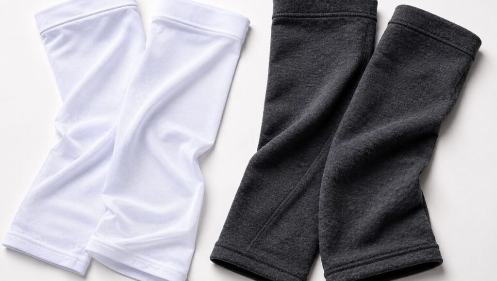 Flat lay comparison of lightweight white UV sun sleeves on left and thicker gray thermal arm warmers on right